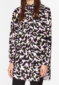Pitkähihaista nappipaitaa, jossa on musta pohja ja abstrakti vaaleanpunainen, valkoinen ja vihreä kuviointi. Kevyt, sileä kangas, rento leikkaus.