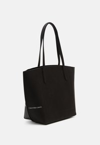 Czarna torba na ramię wykonana z teksturowanego materiału, z dwoma ramiączkami i logo po boku. Prostokątny kształt, minimalistyczny design.