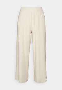 Pantalon large couleur crème avec tissu texturé et taille élastique, présentant des côtes verticales pour un détail supplémentaire.