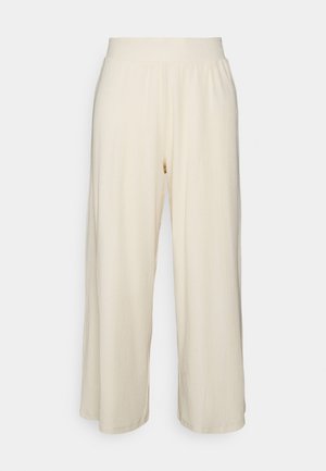 Pantalon large couleur crème avec tissu texturé et taille élastique, présentant des côtes verticales pour un détail supplémentaire.