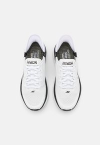 Bijele atletske tenisice s mrežastim gornjim dijelom, vezivanjem na vezice, crnim detaljima i teksturiranom potplatom. Sadrži "SKECHERS GOrun" brendiranje.