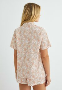 Korte mouwen pyjama set van zachte stof met een roze en witte paisley ontwerp en subtiele groene accenten. Ontspannen pasvorm met korte broek.