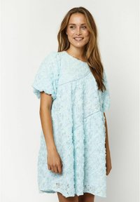 Helles blaues Kleid aus Spitze, mit rundem Halsauschnitt, kurzen Puffärmelchen und einem lockeren Schnitt mit floralen Mustern.