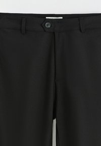 Pantalon noir avec une texture tissée lisse, fermeture à boutons, passants pour ceinture, coupe ajustée et poches latérales.