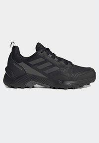 Černé trailové boty Adidas Terrex s polyesterovým svrškem, texturovaným jazykem, vyztuženou špičkou a robustní podrážkou s trakčními hroty.