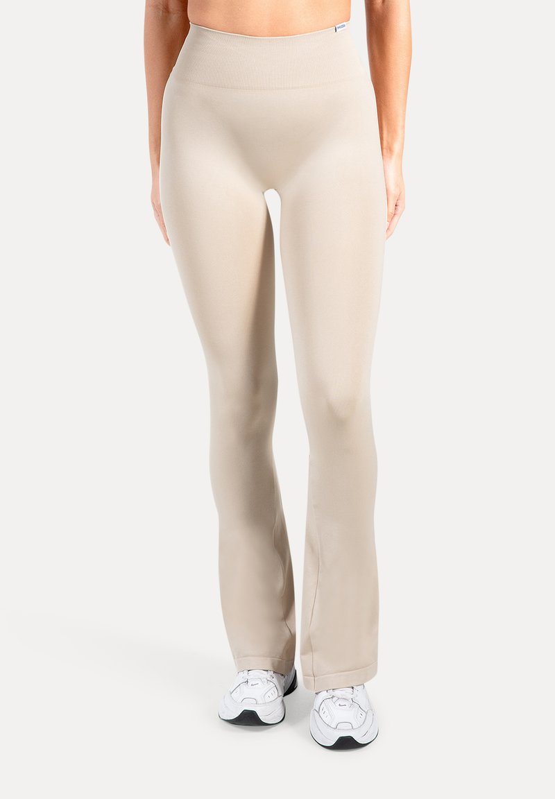 Beige flared leggings met een hoge tailleband, gemaakt van glad, rekbaar materiaal. Heeft een minimalistisch ontwerp zonder zichtbare patronen of accessoires.