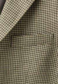 Tessuto a motivo pied-de-poule beige e marrone con dettaglio di tasca e risvolto di una giacca su misura.