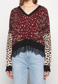 Maglione multicolore a V con stampa floreale e leopardata, orlo a costine nero e dettaglio in pizzo sulla parte inferiore. Vestibilità morbida, maniche lunghe.