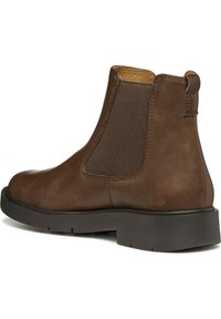 Botas de cuero marrón hasta el tobillo con paneles laterales elásticos, punta redondeada y suela de goma negra. Acabado texturizado con acentos mínimos.