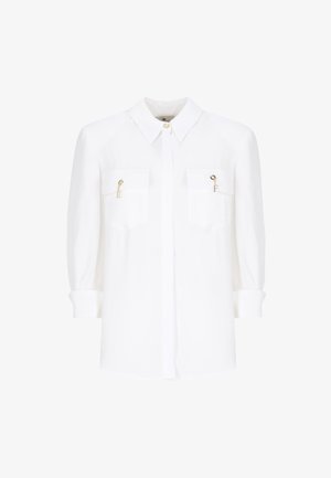 Blusa bianca, tessuto leggero, design con bottoni, maniche arrotolabili, due tasche sul petto con dettagli dorati e logo discreto.