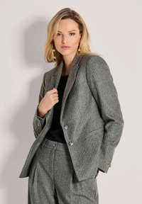 Grijs gestreepte blazer met een getailleerde pasvorm, notch-kleppen, twee knopen en subtiele textuurstof. Gecombineerd met een bijpassende grijze broek.
