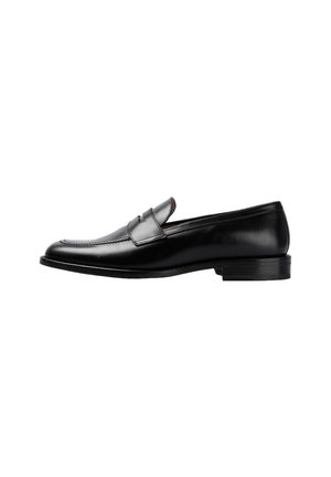 Zapato mocasín de cuero negro con puntera redondeada, detalles de costura, tacón bajo y superficie lisa. Diseño simple sin patrones visibles.