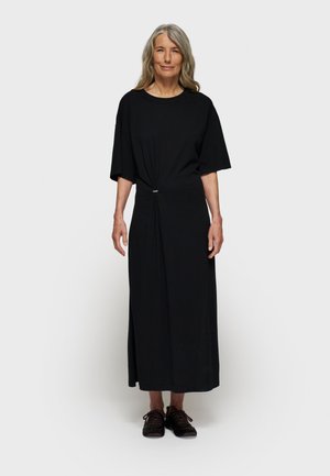 Abito nero fino al ginocchio con una vestibilità rilassata, maniche corte e dettaglio arricciato in vita con un piccolo accento metallico.