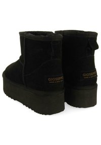 Botines de ante negro con suela de plataforma texturizada. Cuentan con un lazo en la parte trasera para fácil calzado y una etiqueta con el logo en el lateral.