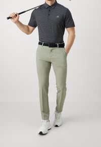 Black and gray striped polo shirt, light green pants, and white athletic shoes. The outfit includes a woven black belt and golf club.