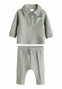 Grå todelt babyoutfit med en krave, lynlåslukning og en brystlomme på toppen samt matchende bukser med elastisk talje, begge i blødt stof.