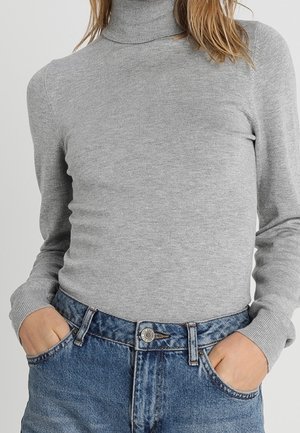 Pull en laine gris à col roulé, en matière douce, avec des manches longues et une coupe près du corps, associé à un jean bleu taille haute.