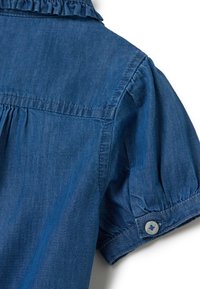 Camicia in denim azzurro chiaro con maniche corte a palloncino, dettagli in rouches al colletto e chiusura a bottone sui polsini.