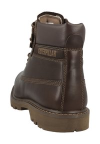 Brune læderankelstøvler med et robust design, der har forstærket syning, en tekstureret sål og "CATERPILLAR"-logoet på siden.