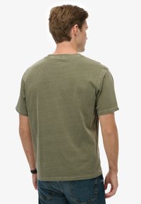 Bawełniany T-shirt w oliwkowo-zielonym kolorze z klasycznym okrągłym dekoltem i krótkimi rękawami, o prostym, nieskomplikowanym wzorze i luźnym kroju.