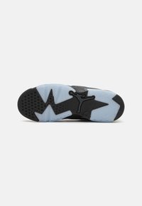 Sole nera della sneaker con una intersuola azzurro ghiaccio. Presenta un motivo in gomma nera testurizzata e un logo Jumpman al centro.