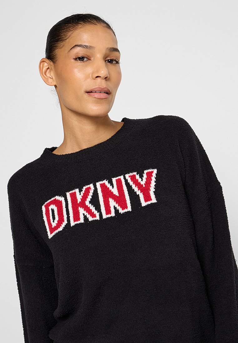 Schwarzer, flauschiger Pullover mit einem auffälligen roten und weißen gestrickten "DKNY"-Logo über der Brust. Rundhalsausschnitt mit langen Ärmeln.
