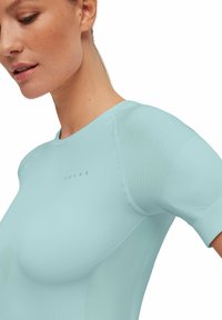 Top sportivo azzurro chiaro, maniche corte, design senza cuciture, dettagli texturizzati sulle spalle e un sottile logo sul davanti.
