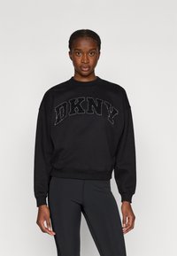 Czarny sweter DKNY z okrągłym dekoltem, z teksturowanym, haftowanym logo w kontrastowym kolorze. Długie rękawy i ściągacze na rękawach.
