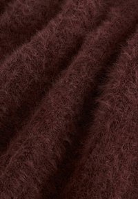 Burgundy fluffig tyg med en strukturerad, mjuk yta. Fibrerna ger en lyxig, varm känsla och har en något ojämn yta.