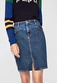 Jeanskjol i mörkblått, med en framficka, klassisk femficksdesign och metallknappstängning. Midjehöjd.