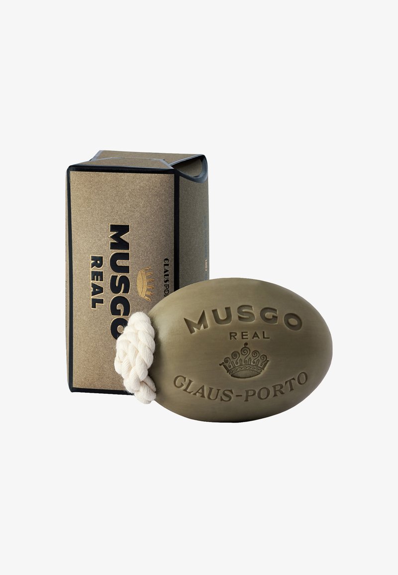 Ovaler olivgrüner Seife mit einem weißen geflochtenen Band. Prägung mit dem Text "MUSGO REAL" und "CLAUS-PORTO." Die Schachtel ist gold und schwarz mit Branding.