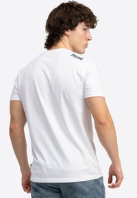 Hvid bomulds T-shirt med korte �ærmer, med et lille sort logo på den øverste del af ryggen og et klassisk rund hals design.