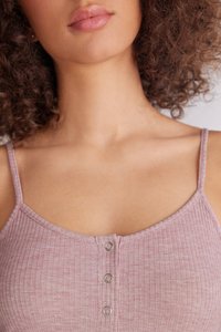 Světlý růžový žebrovaný top s tenkými ramínky a tlačítkovým detailem na výstřihu. Tkanina se jeví jako měkká s jemnou strukturou.