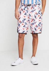 Shorts de bain floraux en tissu blanc, ornés de motifs de fleurs roses et bleues, avec une taille élastique à cordon de serrage et des accents noirs.