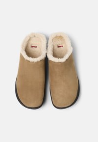 Bruna mockasiner i mocka med en mjuk beige syntetisk pälsfoder, svarta sulor och ett märkt inre med "CAMPER" i rött.