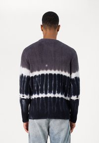 Sweater flou à manches longues avec motif tie-dye ; dégradé bleu marine foncé et gris avec des accents blancs ; col rond ; tissu texturé.