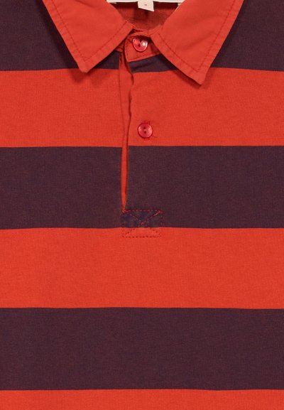 Overhemd met kraag en brede horizontale strepen in donkerpaars en oranje-rood, met twee rode knopen vlakbij de kraag.
