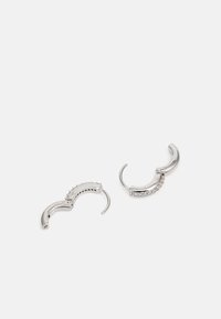 Orecchini in argento con un design curvo e superfici testurizzate, uno decorato con piccoli diamanti trasparenti e l'altro con una finitura liscia.