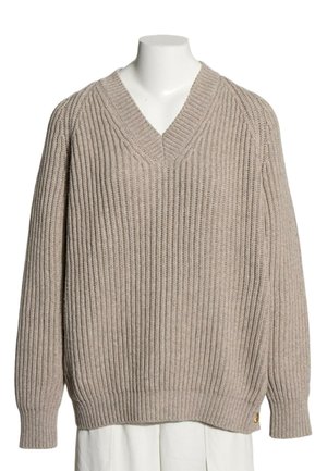 Beżowy sweter z dzianiny z dekoltem w serek i prążkowaną fakturą, prezentowany na białym torsie manekina na białym tle.