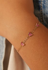 Goldene Armbandkette mit drei rosa Schmetterlingsanhängern, mit glatter Textur und zarten Gliedern.