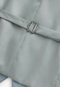 Tissu satin bleu clair avec une texture lisse, comportant une accentue en boucle métallique. Le design inclut des sections pliées et des bords taillés.