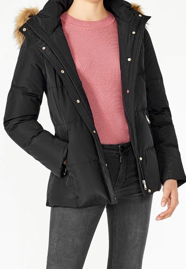 Veste doudoune noire avec capuche en fourrure, dotée d'une fermeture éclair sur le devant, de boutons-pression et de poches latérales, portée sur un pull en maille côtelée rose.