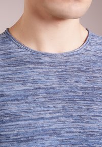 Blue textured short-sleeve t-shirt with a round neckline, featuring a subtle marled pattern in varying shades of blue and gray.