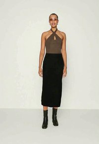 Body castanho com decote em forma de chave, combinado com uma saia midi preta canelada e botas de salto pretas. Design simples e silhueta ajustada.