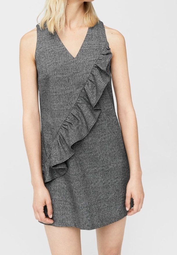 Graues karriertes Kleid mit V-Ausschnitt und asymmetrischem Rüschendetail auf einer Seite. Kurze Länge, ärmelloses Design und strukturierter Stoff.