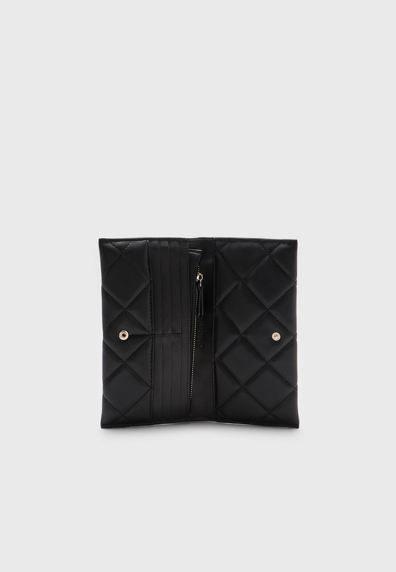 Pochette en simili cuir noir matelassé avec une texture lisse, dotée d'un compartiment zippé et d'une fermeture à pression. Motif géométrique avec des accents en métal.