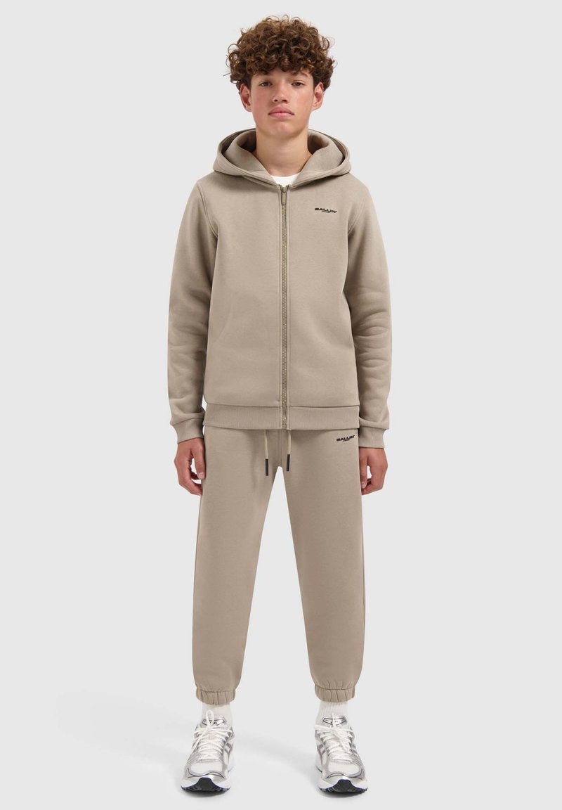 Beige zip-up hoodie met een kangoeroezak en bijpassende tapered joggers. Glad materiaal, geribbelde manchetten en logo-detail op beide stukken.