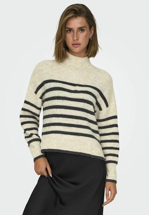 Pull rayé en crème et noir, doté d'un col montant et d'une coupe ample, avec une texture tricot douce et des poignets et un ourlet côtelés.