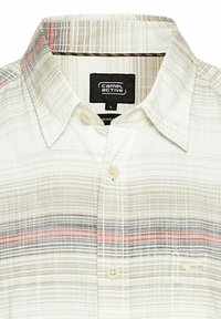 Jasny, zapinany na guziki shirt w kratę z odcieniami beżu, niebieskiego i czerwonego. Posiada kieszeń z przodu oraz standardowy kołnierzyk.