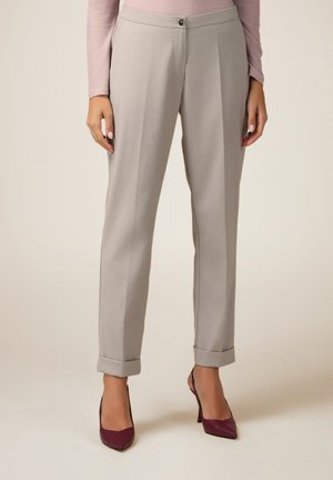 Pantaloni sartoriali grigi chiari con vestibilità dritta, frontale pieghettato, chiusura con bottone, orli arrotolati, abbinati a tacchi alti color bordeaux.